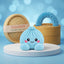 Sky Blue Dumpling Squishy Plush on a white studio podium beside a steamer basket