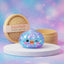 Blue penguin dumpling squishy with pastel galaxy glitter winking on a white podium