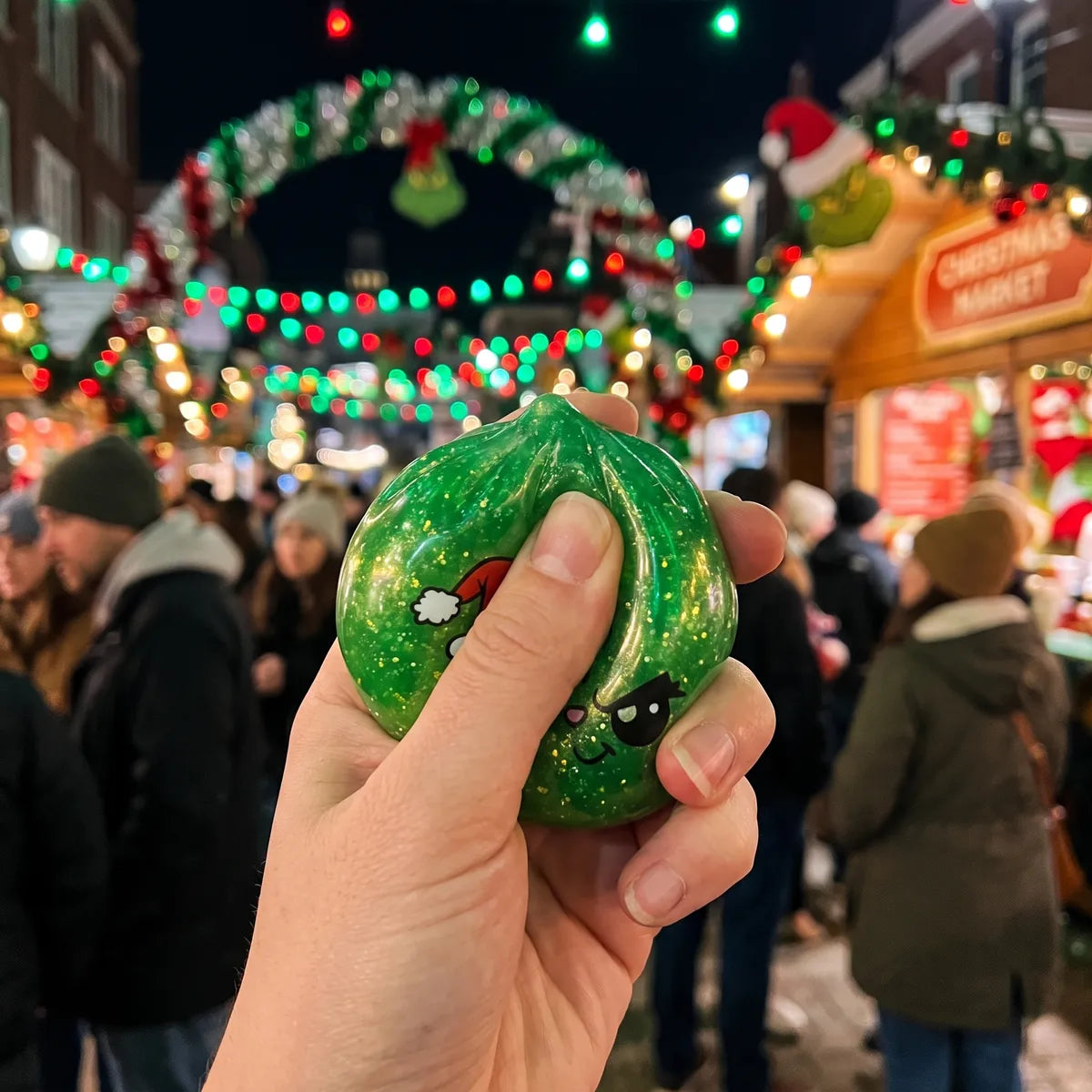 Person squeezing the Grumpy Christmas Evil Dumpling Squishy as a fidget toy at a Christmas market