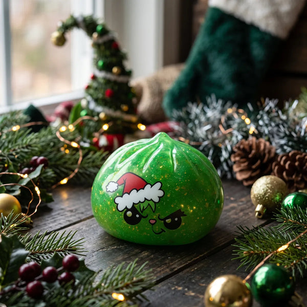 Grumpy Christmas Evil Dumpling Squishy displayed on a wooden table with tinsel and pine cones
