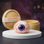 Eyeball Halloween dumpling squishy with red veins and a violet iris on a white podium