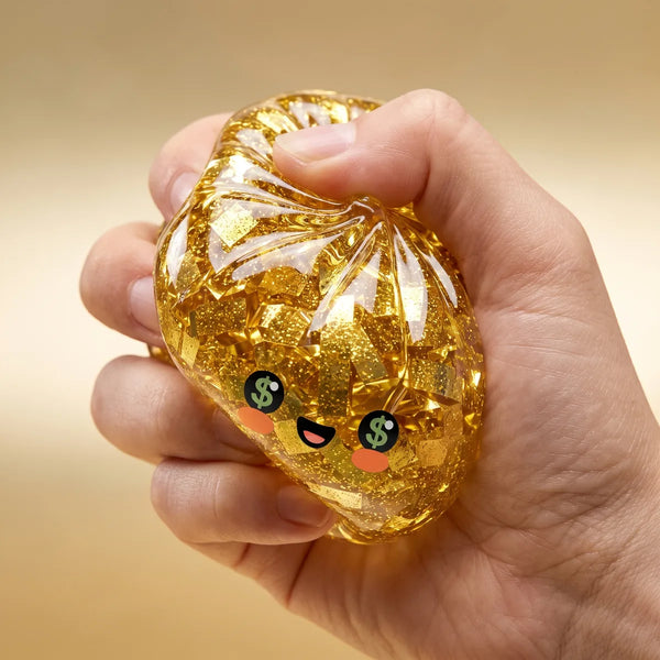 Gold Dumpling Squishy squeezed inside a closed fist showing its stretchy glitter-filled texture