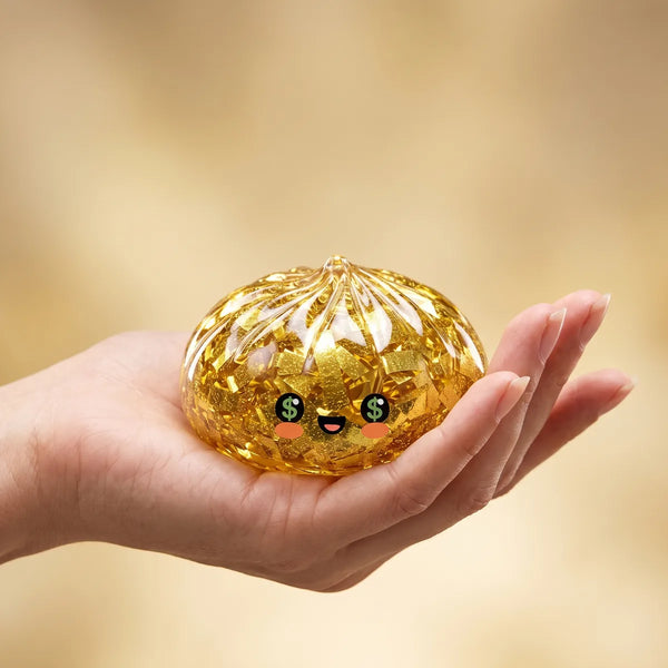 Gold Dumpling Squishy resting in an open palm to show its soft hand-held size