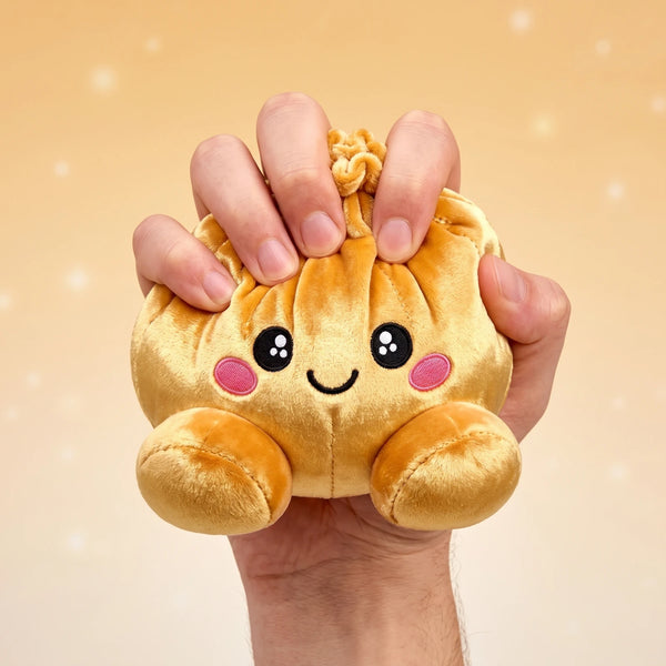 Hand gripping and squishing the Royal Gold Dumpling Squishy Plush