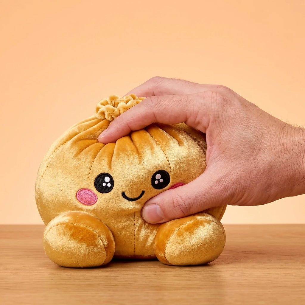 Fingers pinching the Royal Gold Dumpling Squishy Plush to show how soft it is