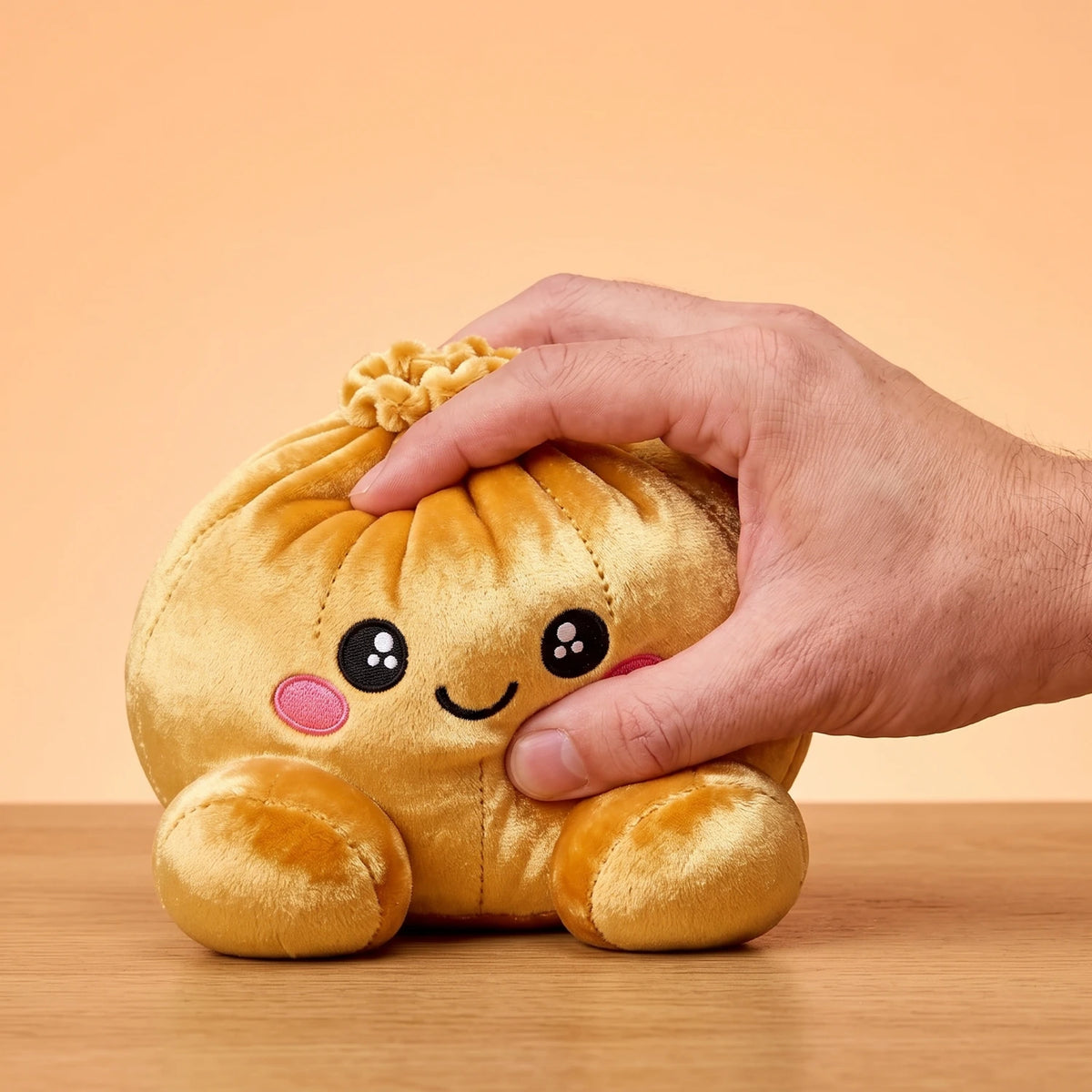 Fingers pinching the Royal Gold Dumpling Squishy Plush to show how soft it is