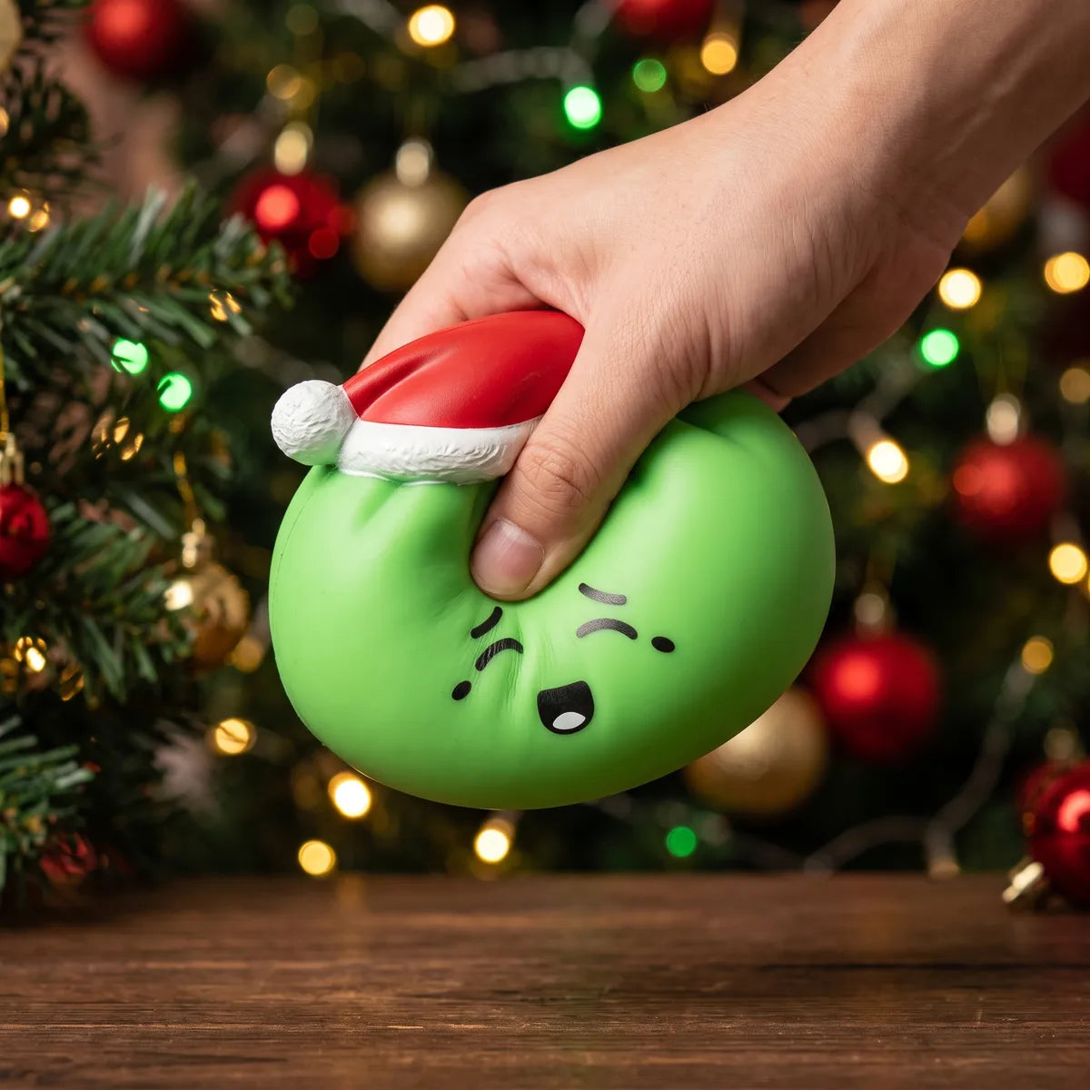 Elf Green Christmas Hat Dumpling Squishy pressed flat under a hand before it slowly rises back