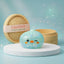 Green penguin dumpling squishy in frosted mint with iridescent flakes beside a bamboo steamer