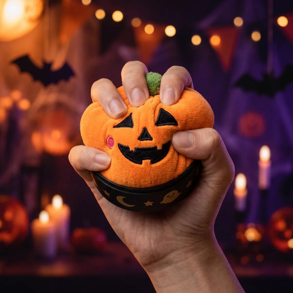 Hand pressing down on the soft pumpkin plush from the Spooky Halloween Dumpling Squishy Plush 5 Pieces Set
