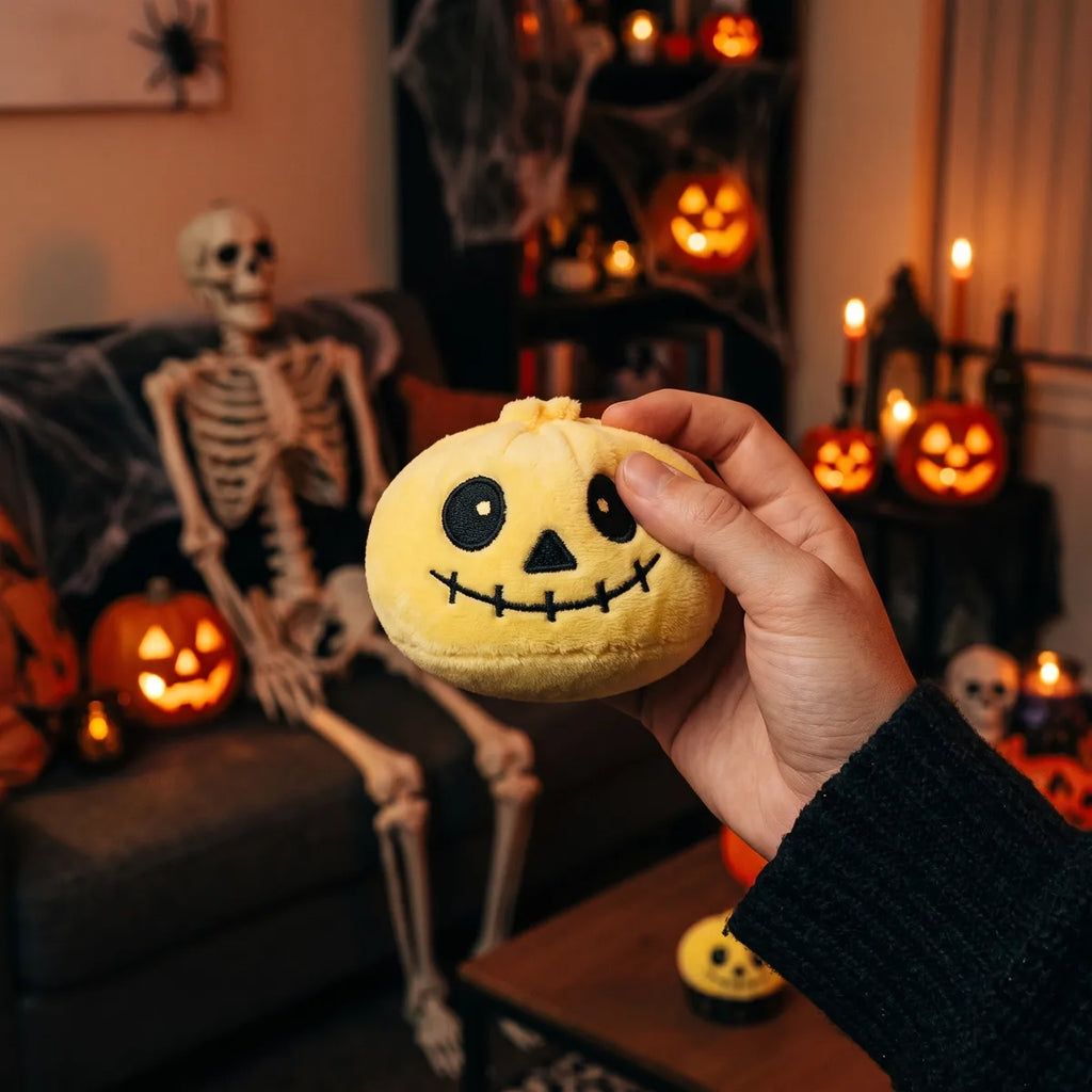 Person squeezing the Grinning Halloween Skeleton Dumpling Squishy Plush as a fidget toy on a sofa with skeleton decor