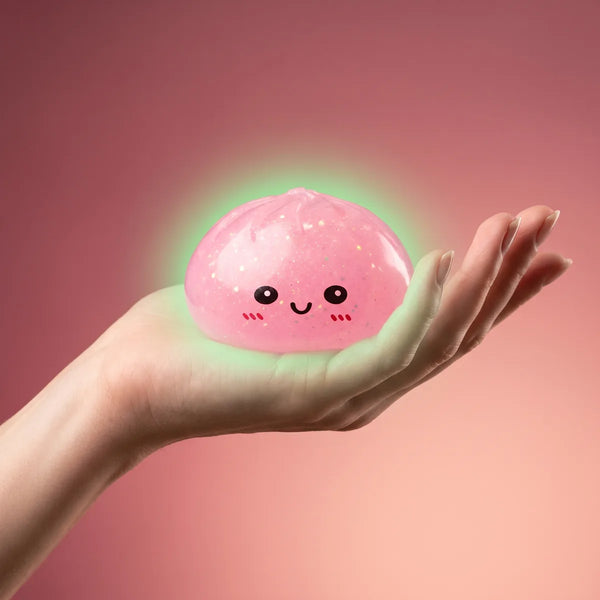 Hand holding a glow in the dark glitter dumpling squishy