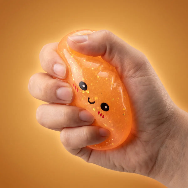 Hand squeezing a glow in the dark glitter dumpling squishy