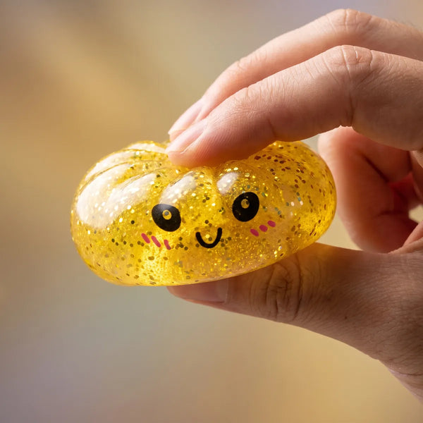 Hand squeezing a mini glitter dumpling squishy
