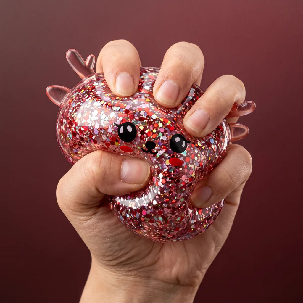 Hand squeezing the Twinkling Mystery Reindeer Dumpling Squishy so the glitter swirls inside