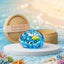 Ocean glitter dumpling squishy with a fish and shells sealed inside on a beach podium