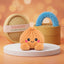 Tangerine Orange Dumpling Squishy Plush on a white studio podium beside a steamer basket