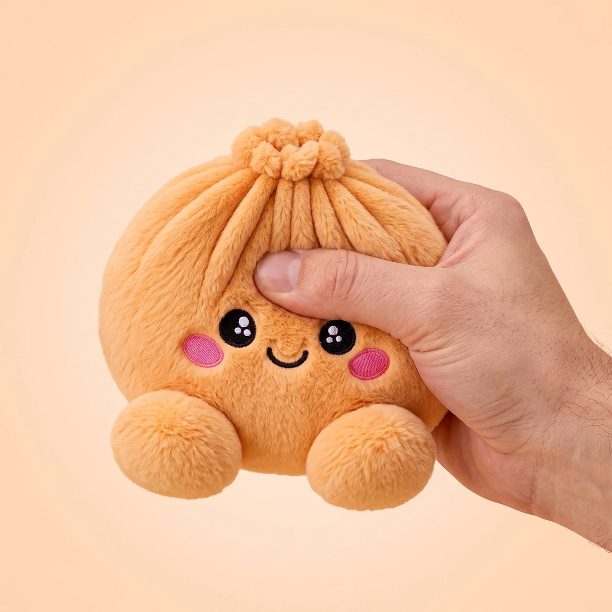 Fingers pinching the Tangerine Orange Dumpling Squishy Plush to show how soft it is