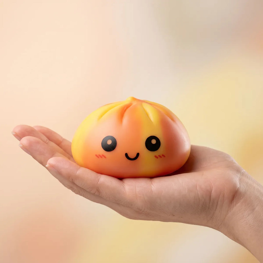 Hand holding the 8.5 cm orange tie dye dumpling squishy for size reference