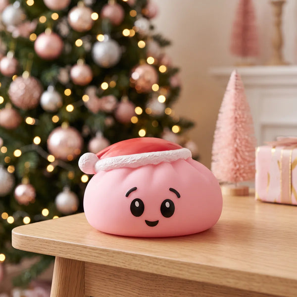 Sugar Pink Christmas Hat Dumpling Squishy displayed on a wooden shelf beside a pink Christmas tree