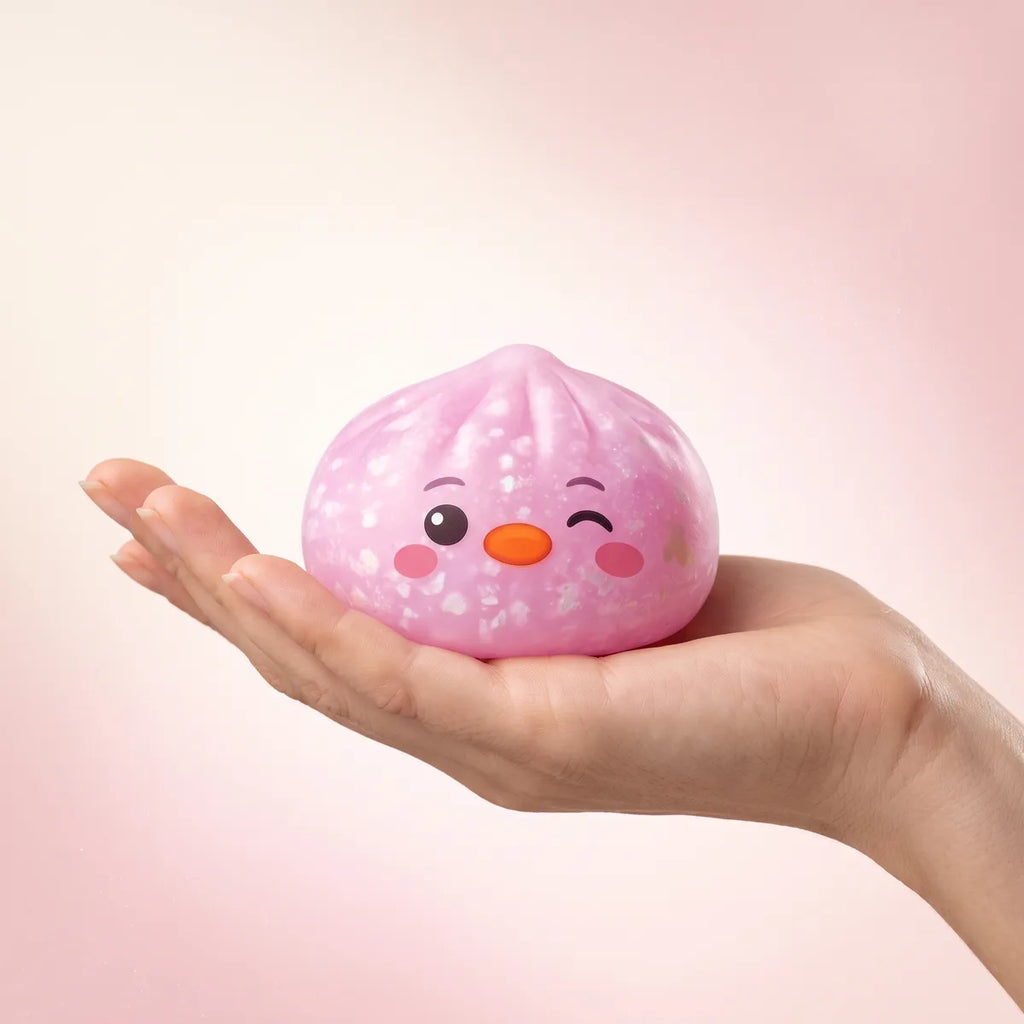 Hand holding the 5.5 cm pink penguin dumpling squishy to show its size
