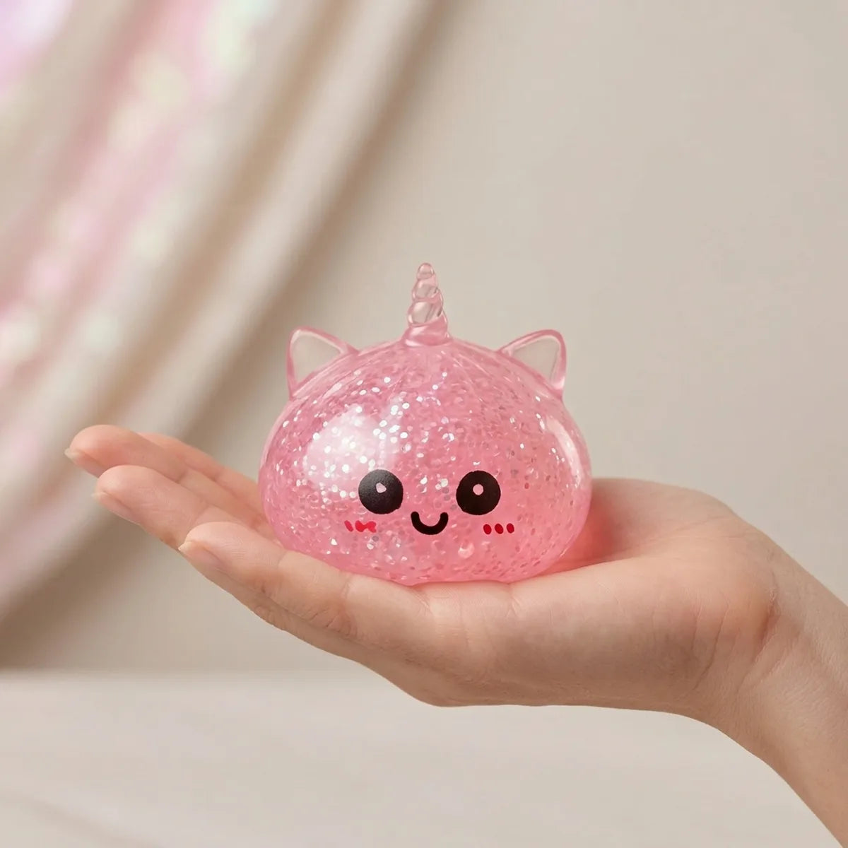 Hand holding the 5.5 cm pink unicorn glitter dumpling squishy to show its size