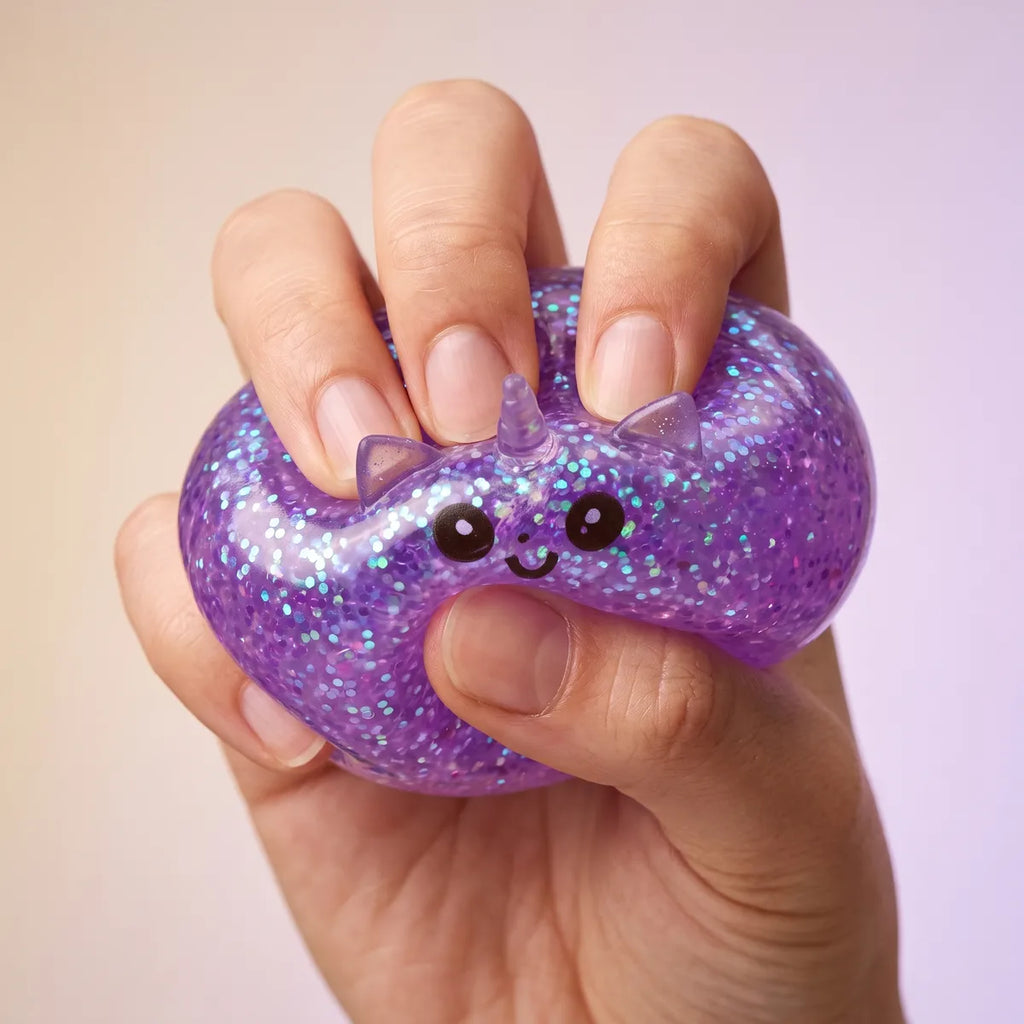 Fingers pressing the purple unicorn glitter dumpling squishy to show its slow rise