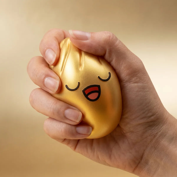 Hands playing with the rare gold dumpling squishy stress toy