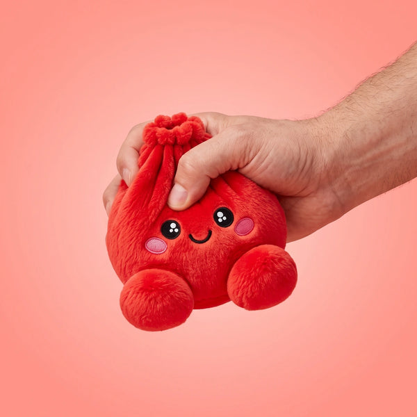 Fingers pinching the Ruby Red Dumpling Squishy Plush to show how soft it is