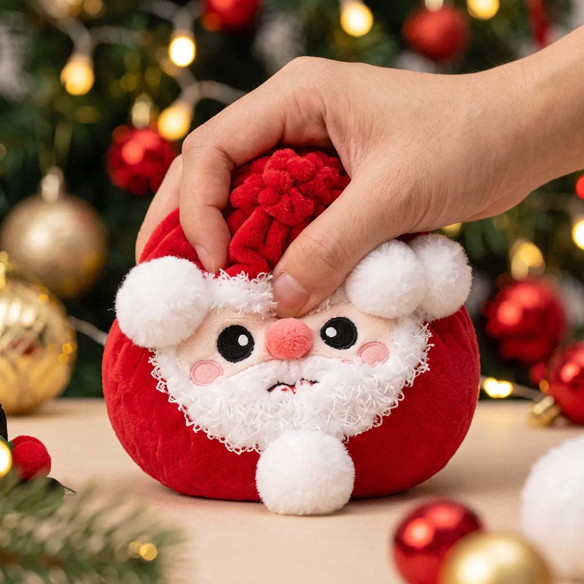 Hand pressing down on the soft Merry Santa Claus Dumpling Squishy Plush