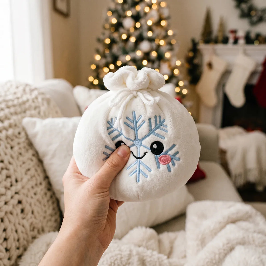 Person squeezing the Winter Snowflake Dumpling Squishy Plush as a fidget toy on a cozy white sofa