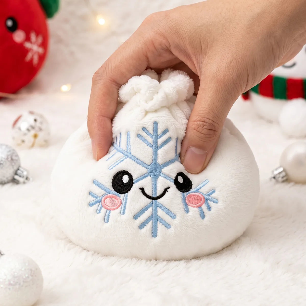 Hand pressing down on the soft Winter Snowflake Dumpling Squishy Plush