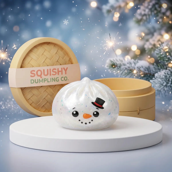 Glittery Snowman Dumpling Squishy on a white studio podium beside a steamer basket
