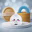 Marshmallow White Dumpling Squishy Plush on a white studio podium beside a steamer basket