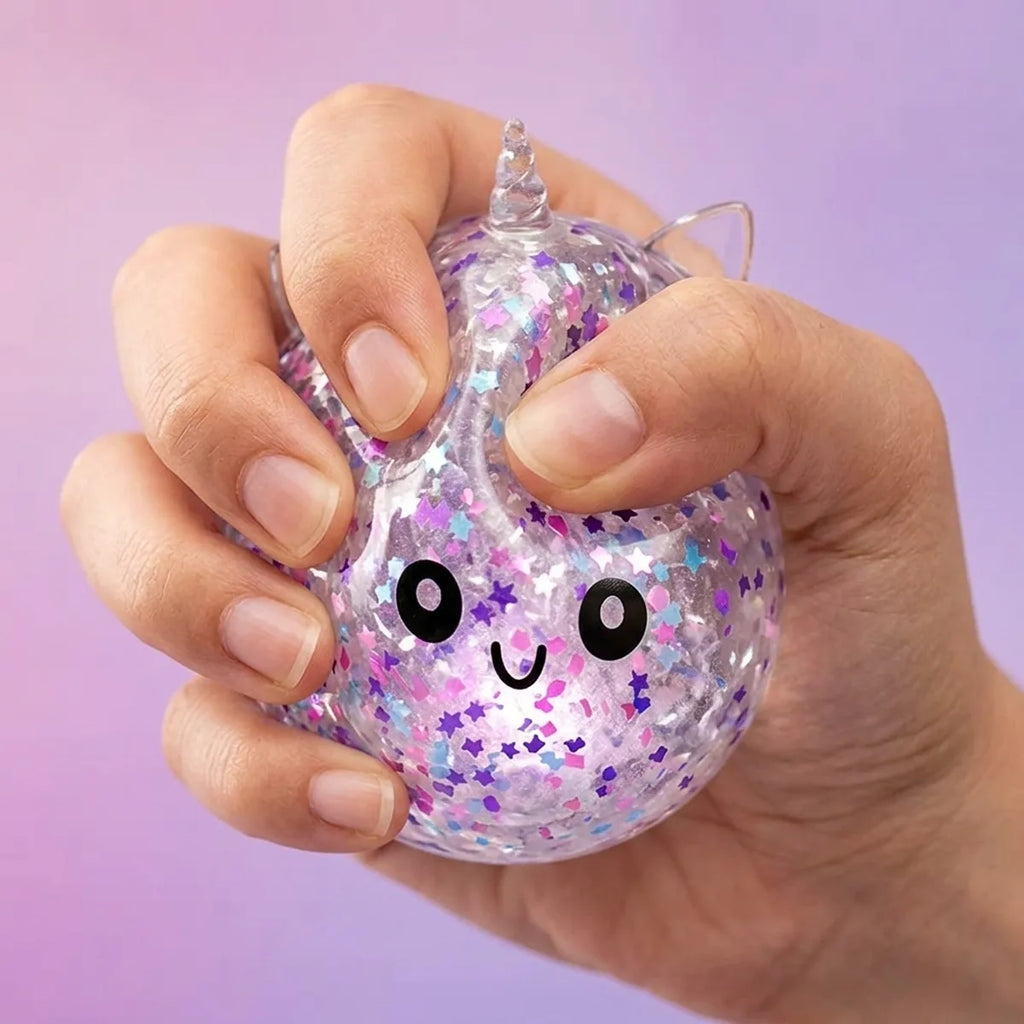 Fingers pressing the white unicorn sparkle dumpling squishy to show its slow rise