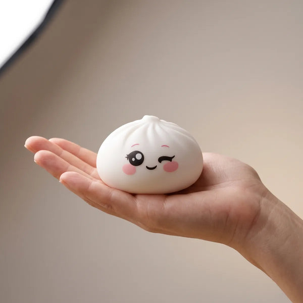 Milky White Wink Dumpling Squishy resting on an open palm to show its real size