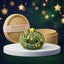 Twinkle Xmas Tree Dumpling Squishy Plush on a white studio podium beside a steamer basket
