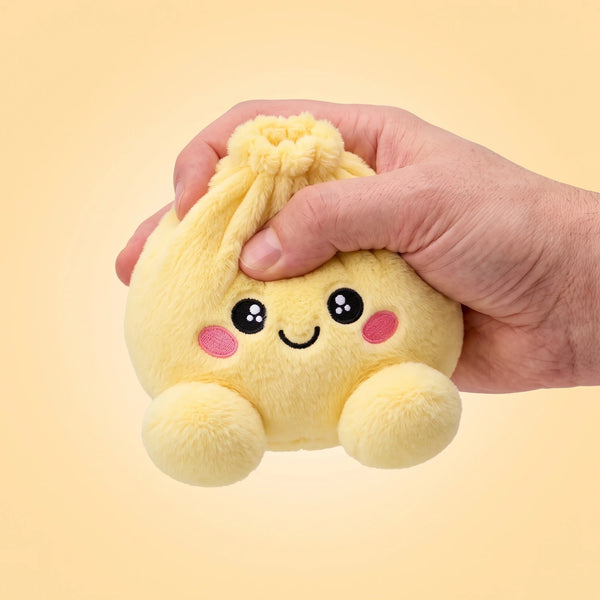 Fingers pinching the Lemon Yellow Dumpling Squishy Plush to show how soft it is