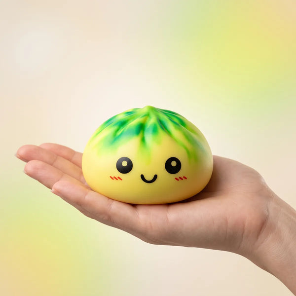 Hand holding the 8.5 cm yellow tie dye dumpling squishy for size comparison